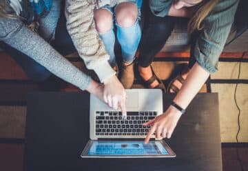 three person pointing the silver laptop computer