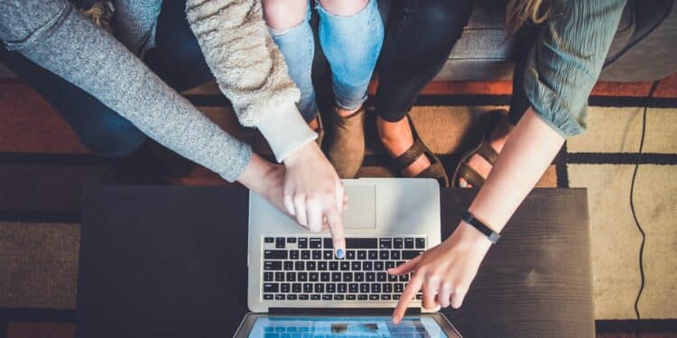 three person pointing the silver laptop computer