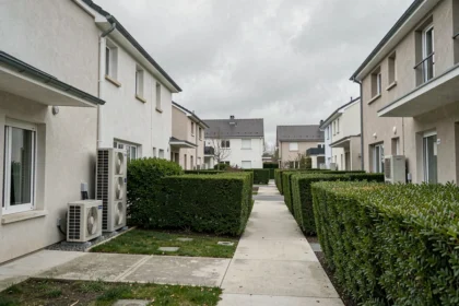 Vue grand angle d'un quartier résidentiel en Seine-Saint-Denis avec plusieurs pompes à chaleur installées sur les façades extérieures des maisons